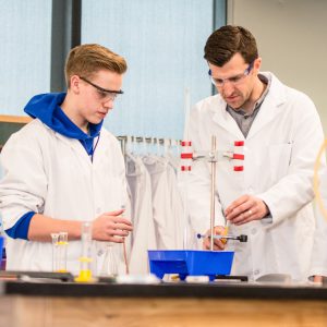 High school teacher with student conducting science experiment